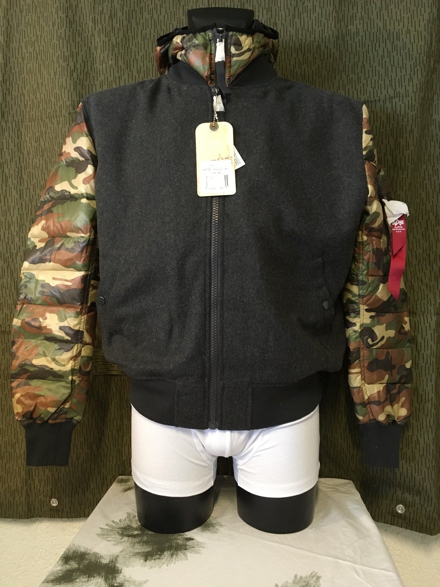Schwarze und Camouflage-Jacke auf der Schaufensterpuppe; weiße Unterwäsche, grüner Camouflage-Hintergrund.