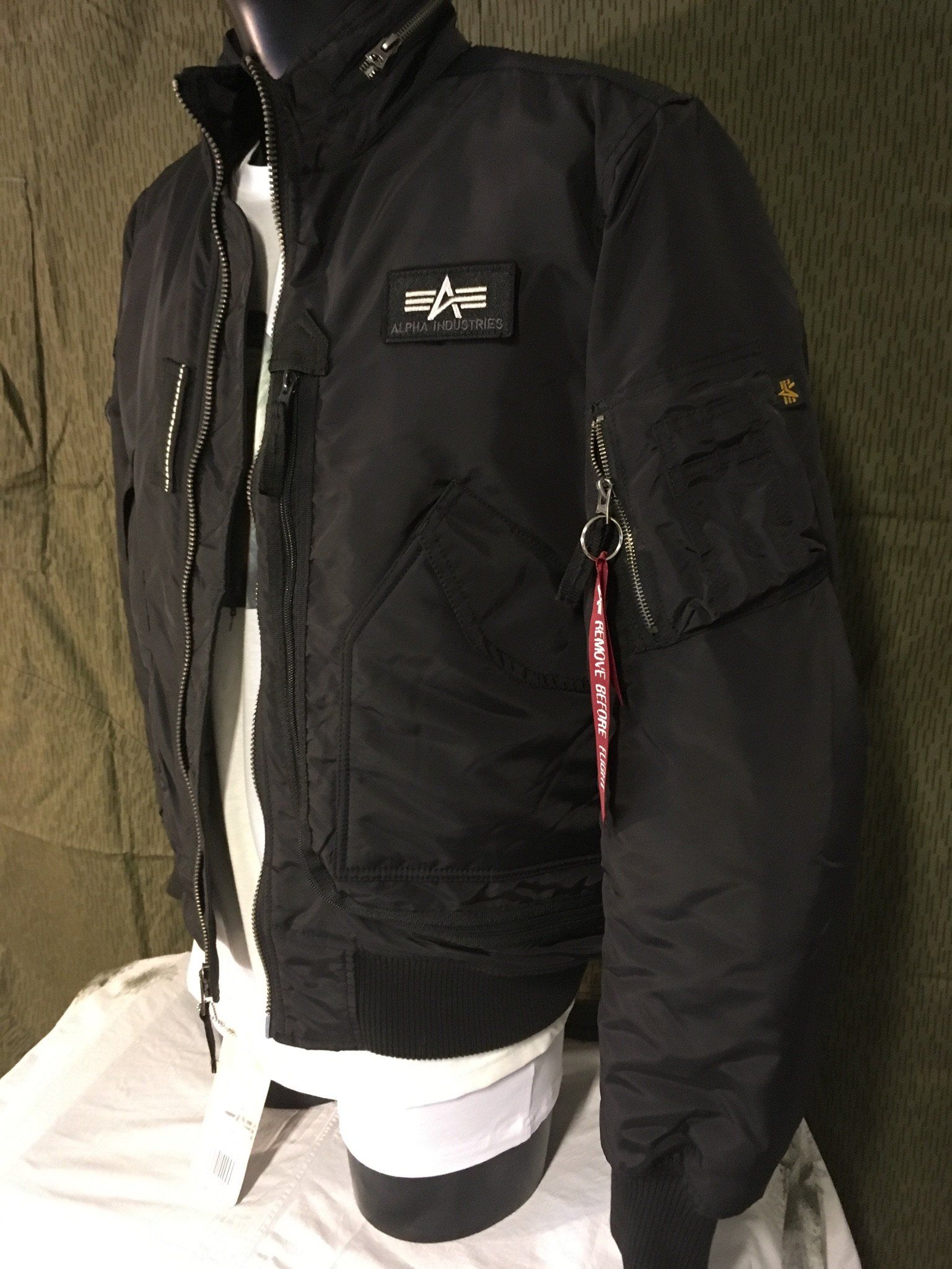 Schwarze Bomberjacke von Alpha Industries an einer Schaufensterpuppe, darunter ist ein weißes Hemd zu sehen.
