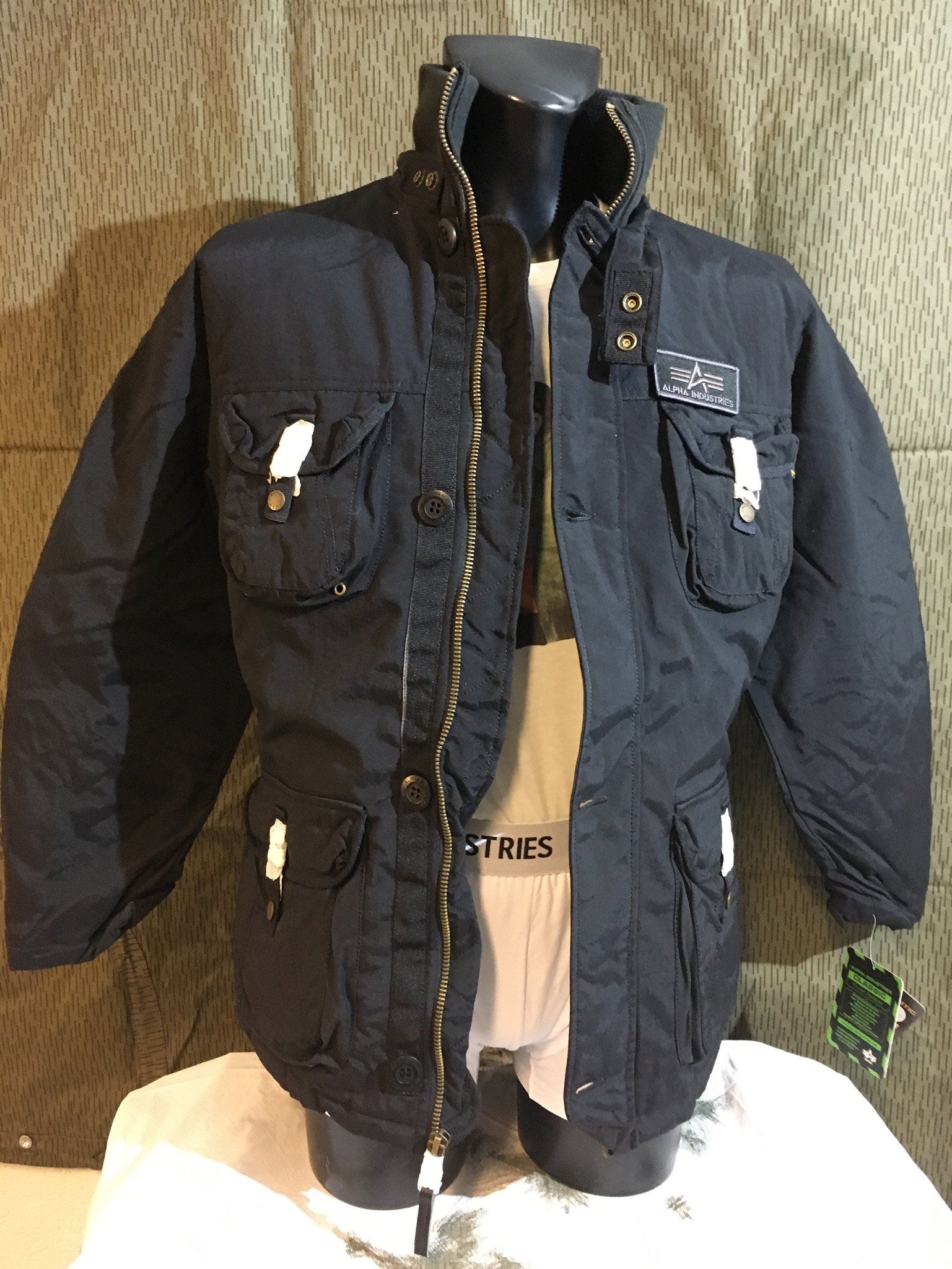 Schwarze Jacke mit mehreren Taschen an einer Schaufensterpuppe.