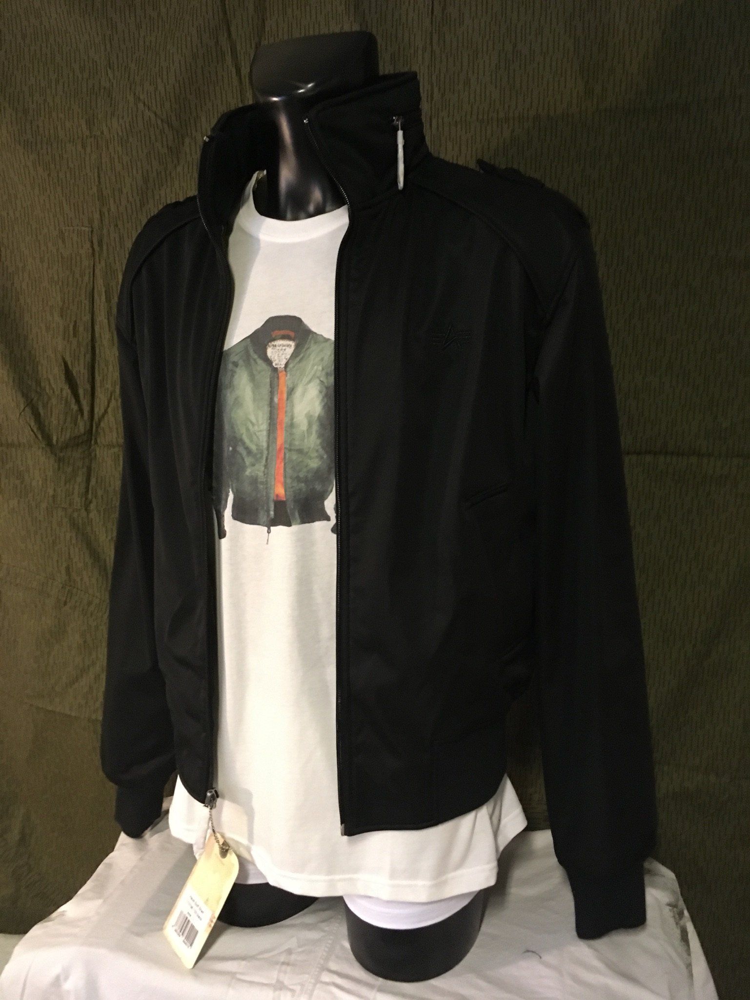Schwarze Jacke über einem weißen T-Shirt auf einer Schaufensterpuppe. Das T-Shirt hat einen grünen Jackenaufdruck.