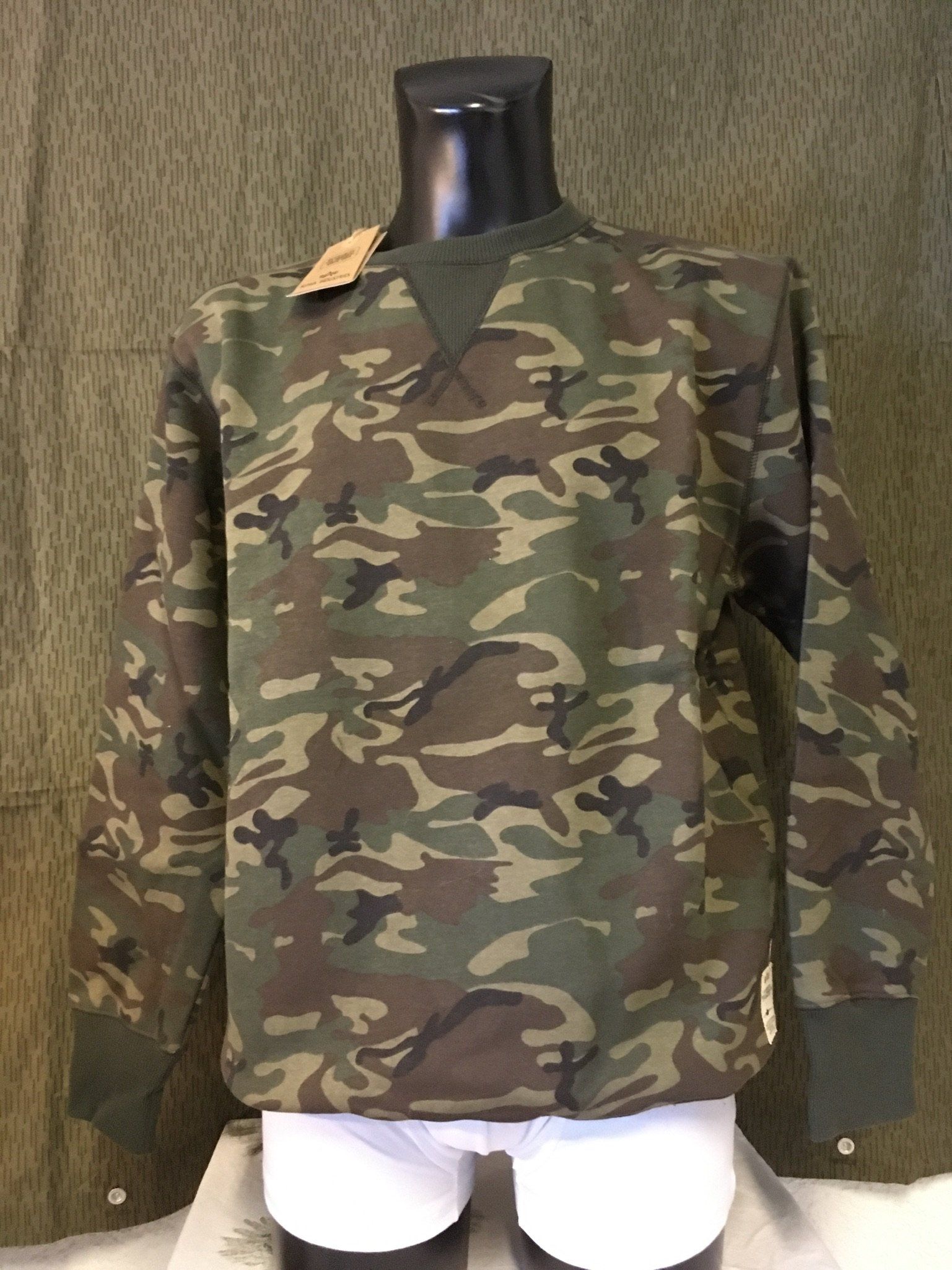 Camouflage-Sweatshirt auf einer schwarzen Schaufensterpuppe; grün-brauner Aufdruck, Bündchen und Kragen sind einfarbig grün.