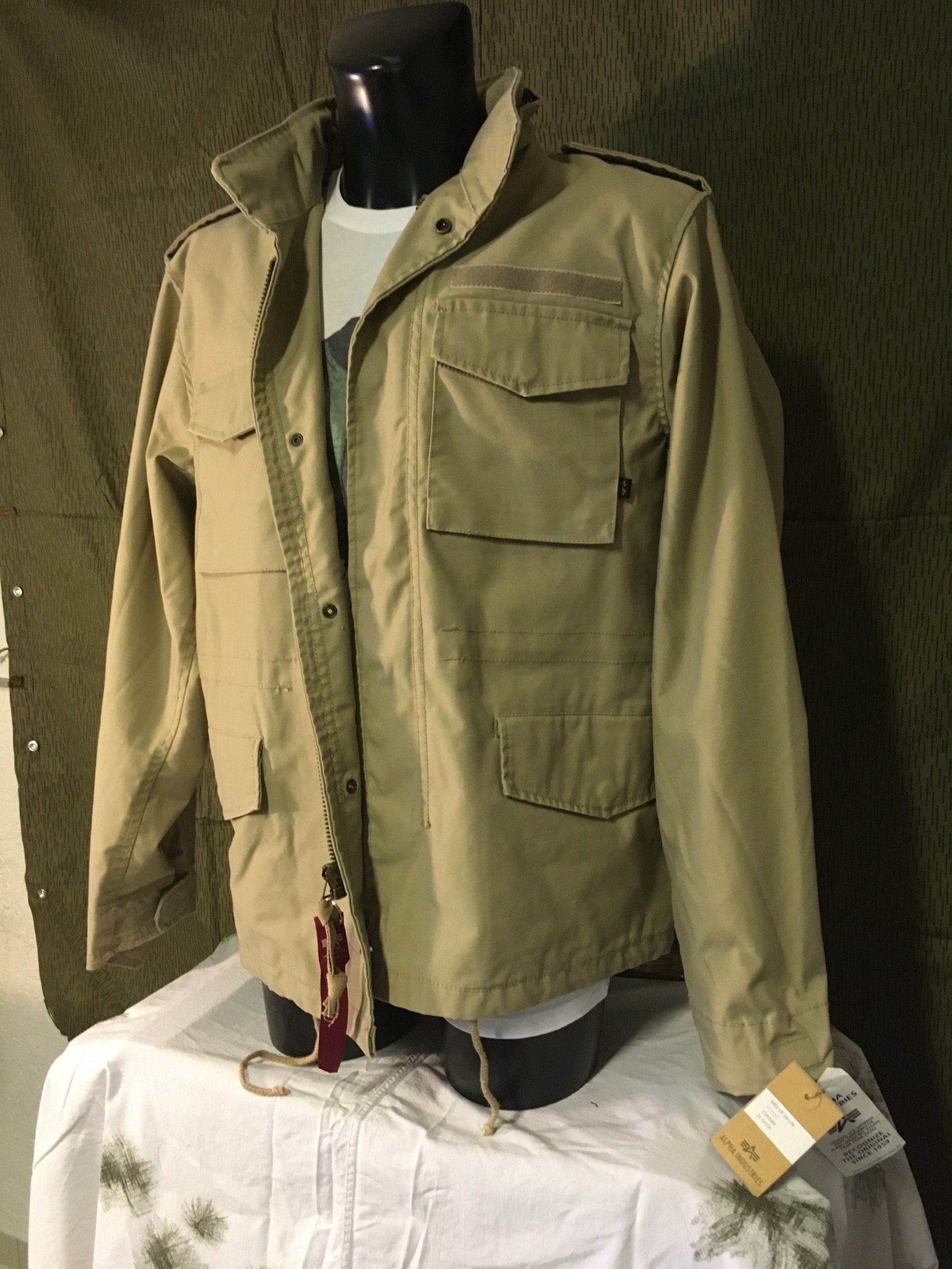 Hellbraune Jacke im Militärstil auf einer Schaufensterpuppe über einem weißen T-Shirt.