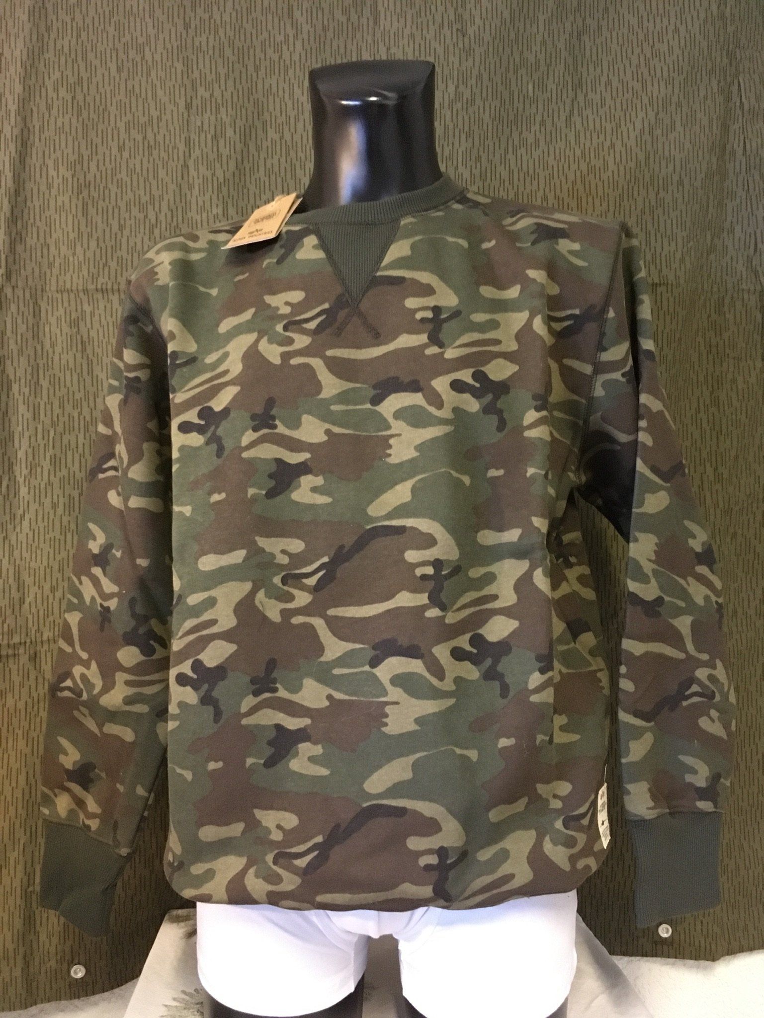 Camouflage-Sweatshirt auf einer Schaufensterpuppe, mit grünem Besatz und einem Etikett.