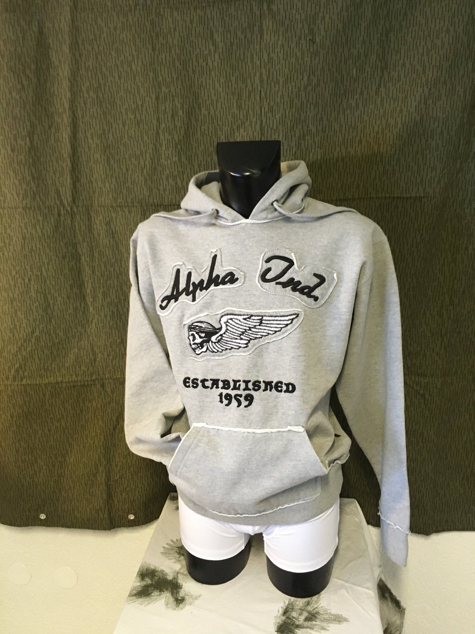 Grauer Kapuzenpullover mit „Alpha Phi Omega“-Text und Logo auf einer Schaufensterpuppe.