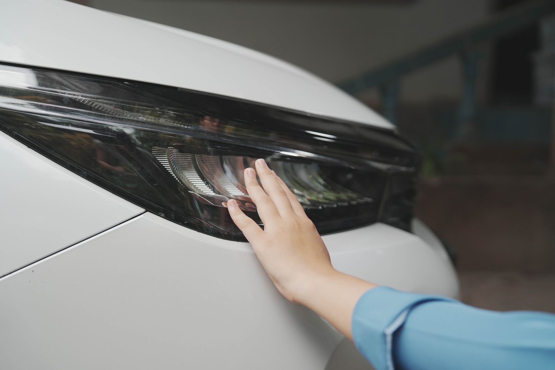Hand on white car headlight for auto body restoration