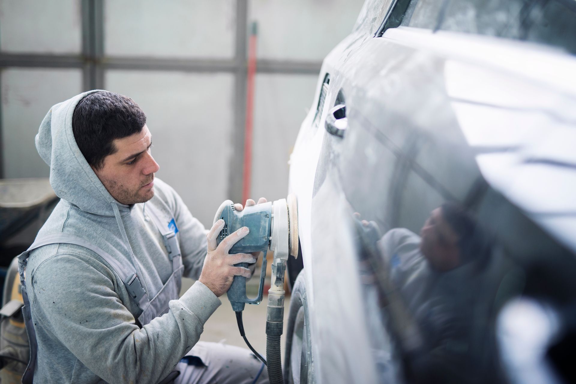 Auto body technician polishing a vehicle exterior with a power buffer Auto body technician polishing a vehicle exterior with a power buffer