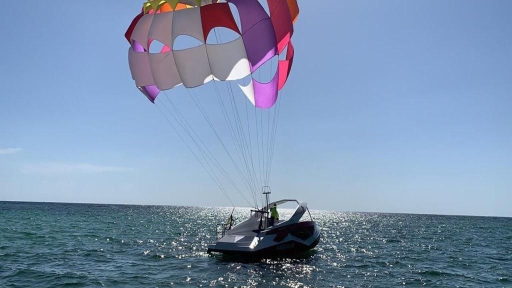 Colorful parasail above a small boat on open water under a clear blue sky