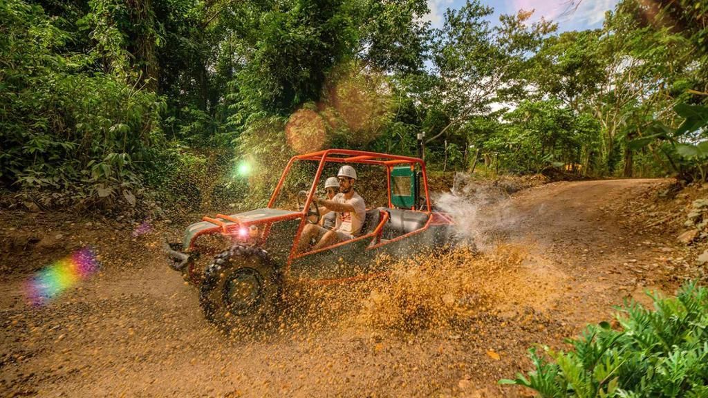 Red off-road jeep splashing through muddy water on a forest trail