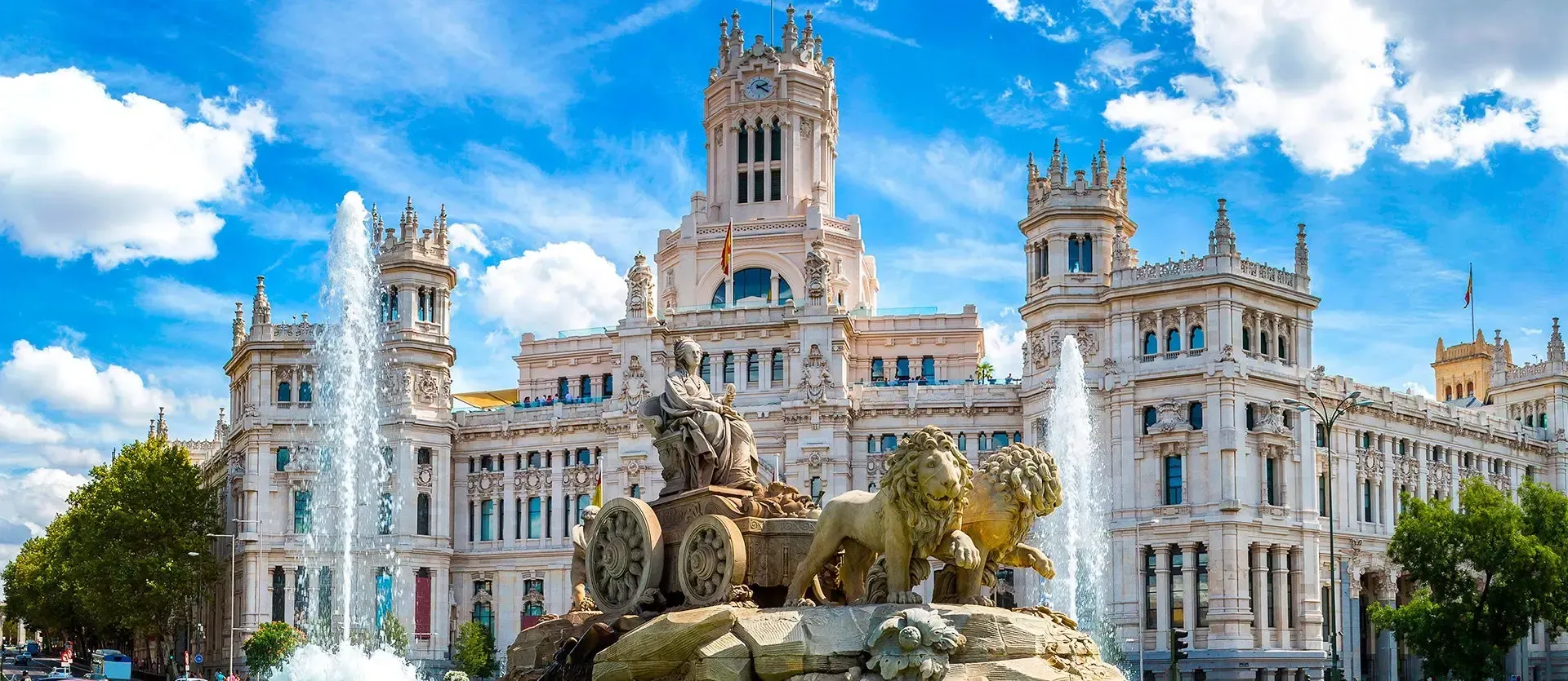 Grand white ornate palace with towers and fountains beneath a bright blue sky