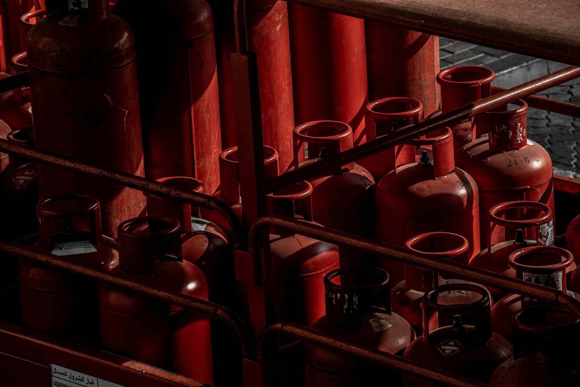 Un montón de botellas de gas rojas están apiladas una encima de otra en un estante.