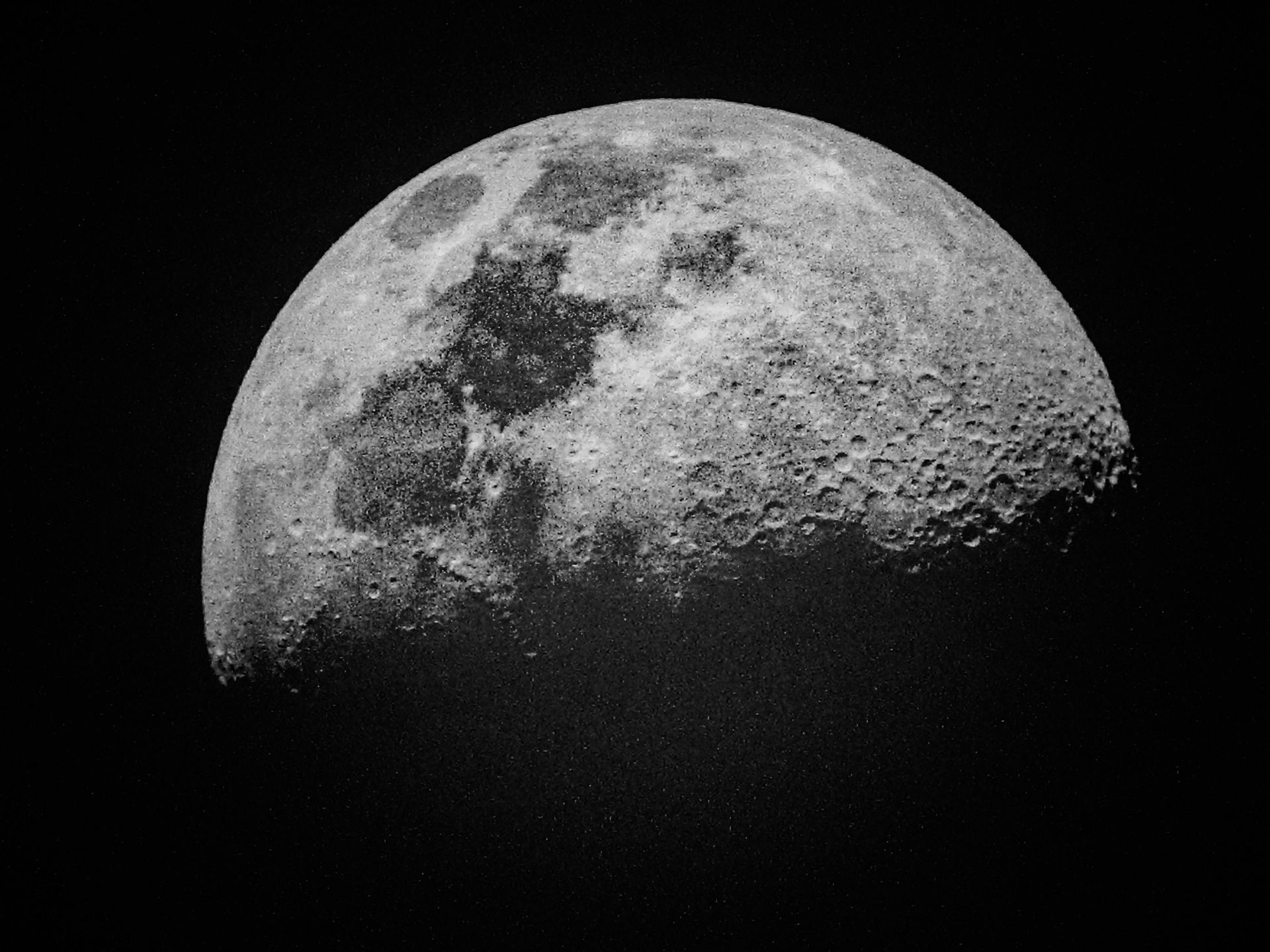 Una fotografía en blanco y negro de una media luna en el cielo nocturno.
