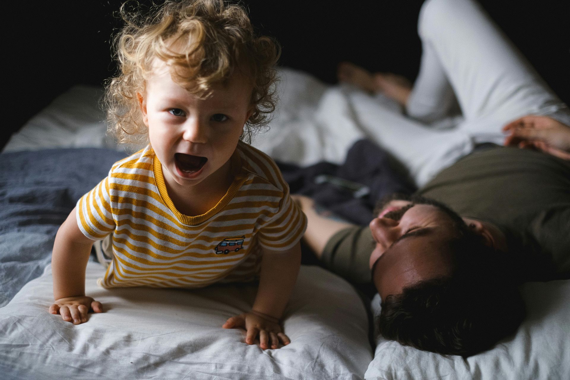 Un hombre y un niño pequeño están jugando en una cama.