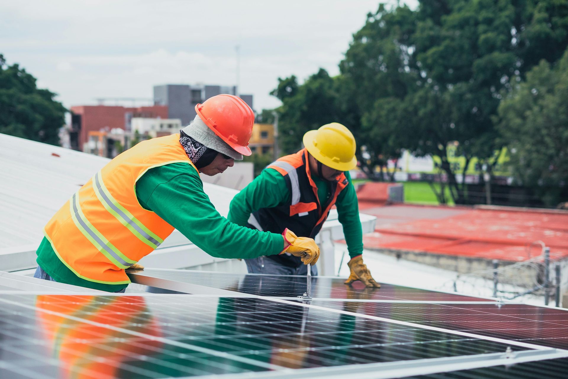 Dos hombres están instalando paneles solares en el tejado de un edificio.