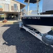 A boat is parked on a trailer in front of a house.