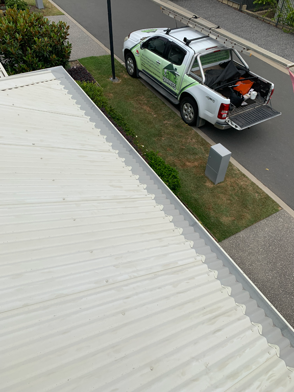 A Man Is Fixing A Gutter On A House With A Drill — Gutter Guard In Harrington, NSW