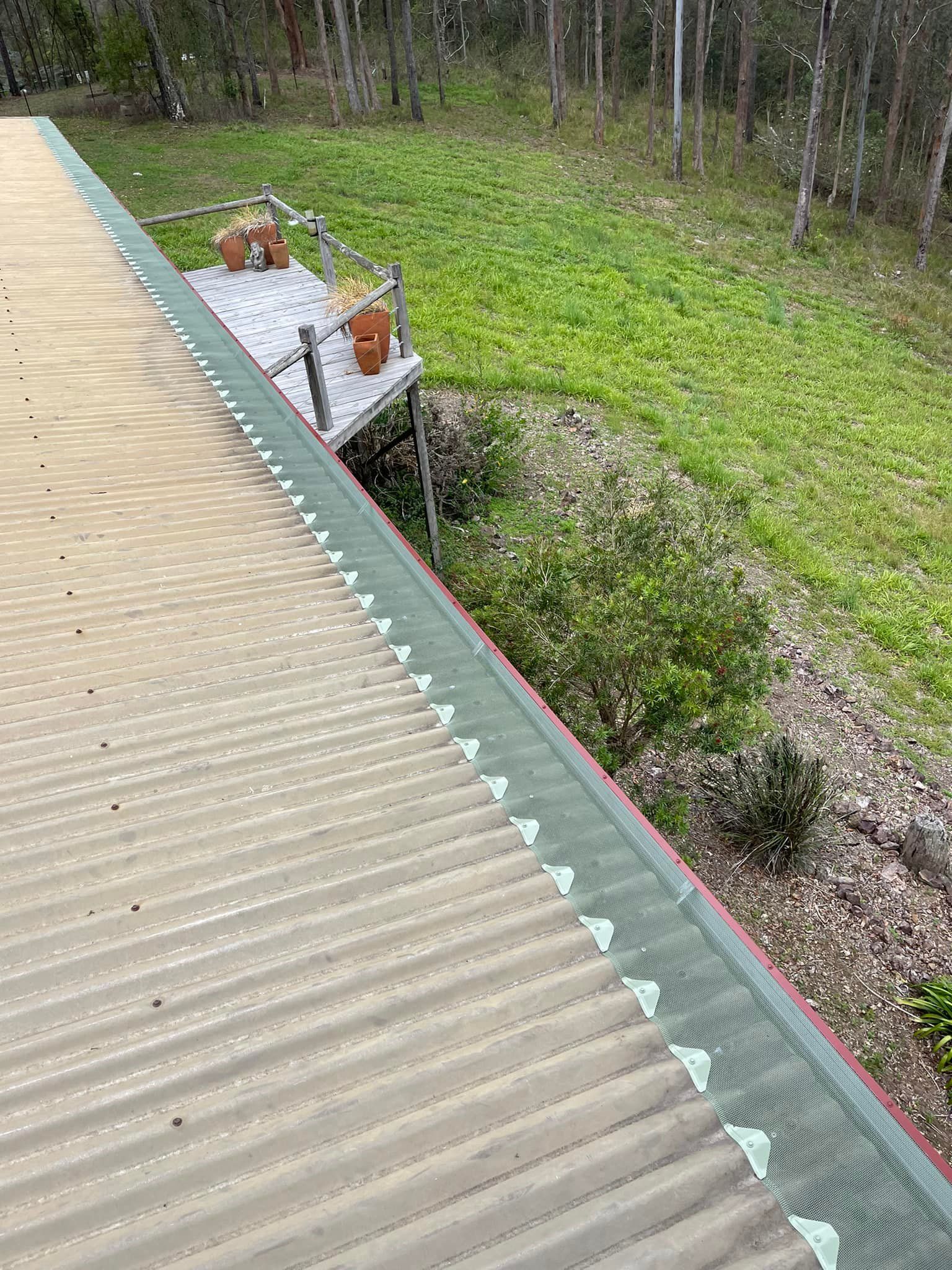 Corrugated metal roof with green trim and a deck in a grassy area.— Gutter Guard In Lake Cathie, NSW
