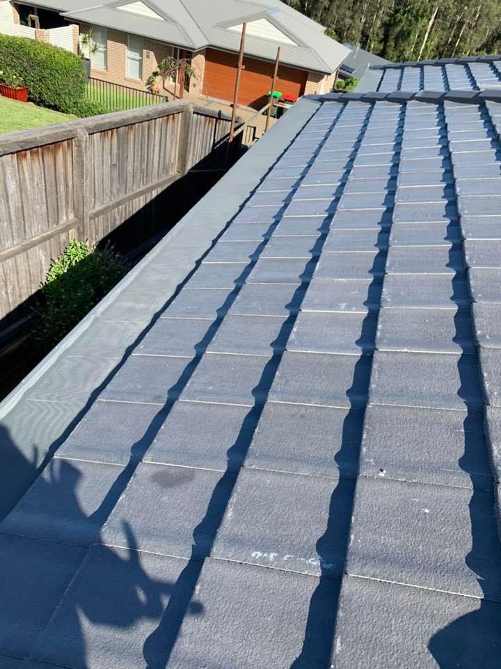 Gray roof tiles with shadows cast on them, a gutter, and a wooden fence.  — Gutter Guard In Port Macquarie, NSW