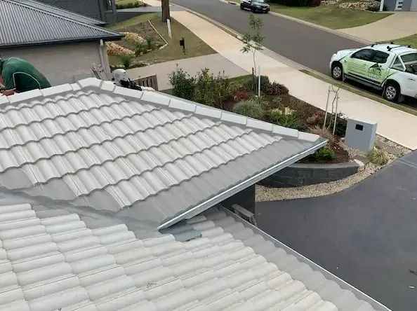Gray tiled roof with a gutter, overlooking a driveway, landscaping, and a street — Gutter Guard In Lake Cathie, NSW