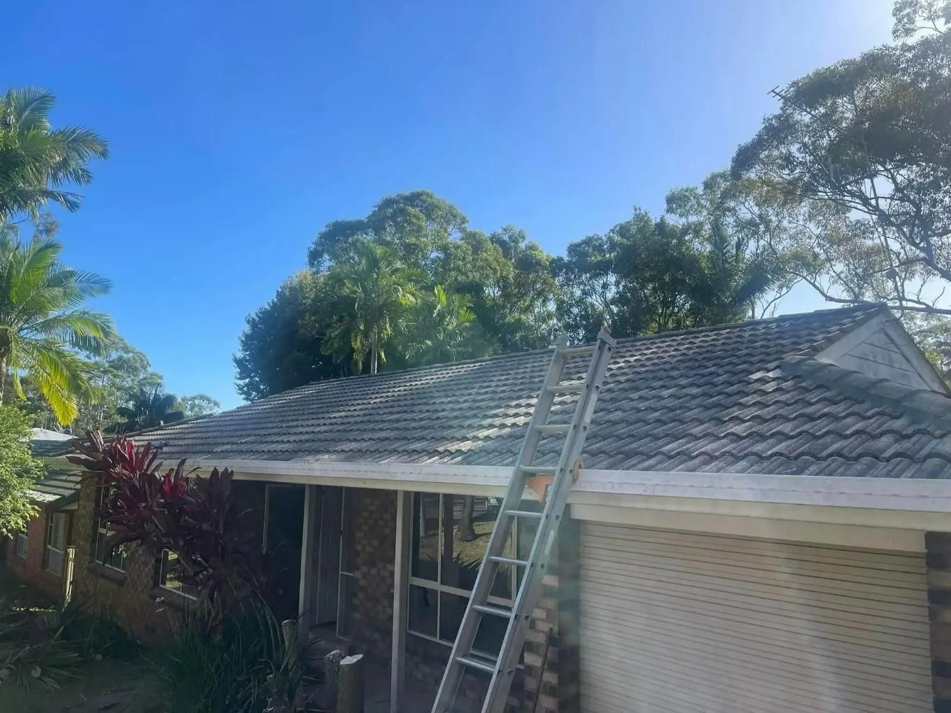 A Ladder Is Sitting On The Roof Of A House — Gutter Guard In Lake Cathie, NSW