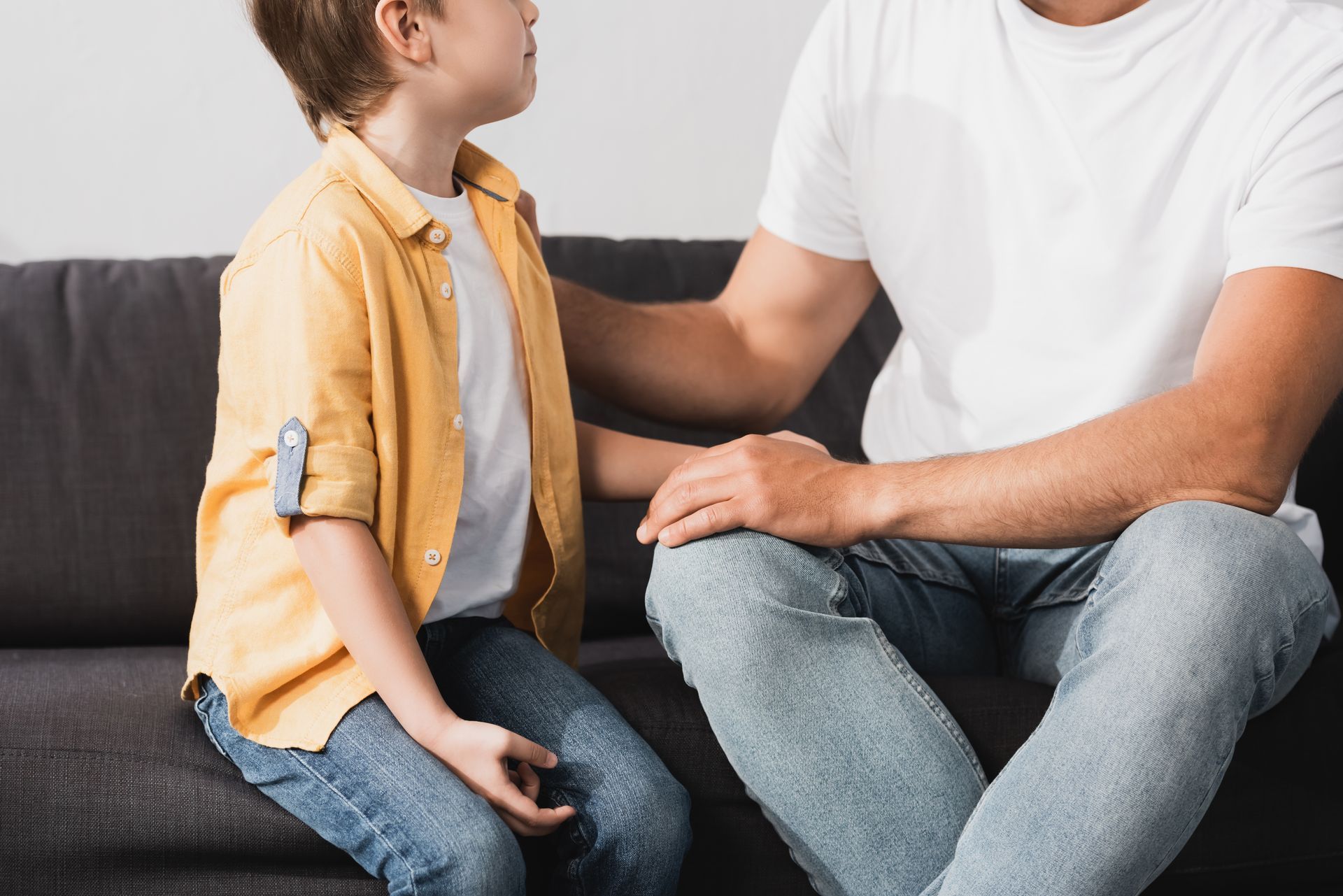 Child and adult sitting on a sofa, talking with hands resting on the child’s lap Child and adult sitting on a sofa, talking with hands resting on the child’s lap