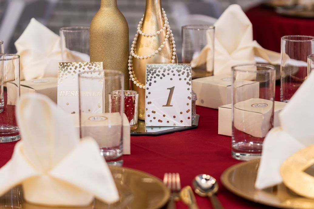Elegant table setting with gold accents, red tablecloth, and table number
