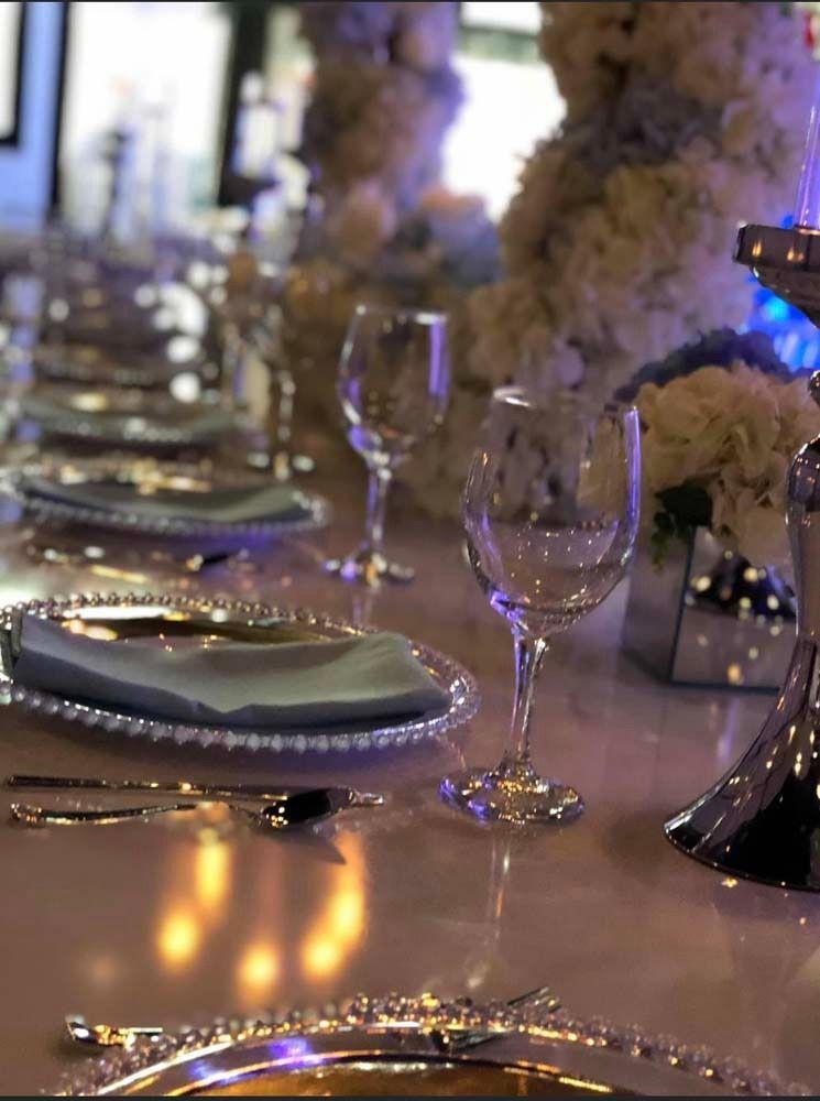 Elegant table setting with silverware, glassware, and floral centerpieces.