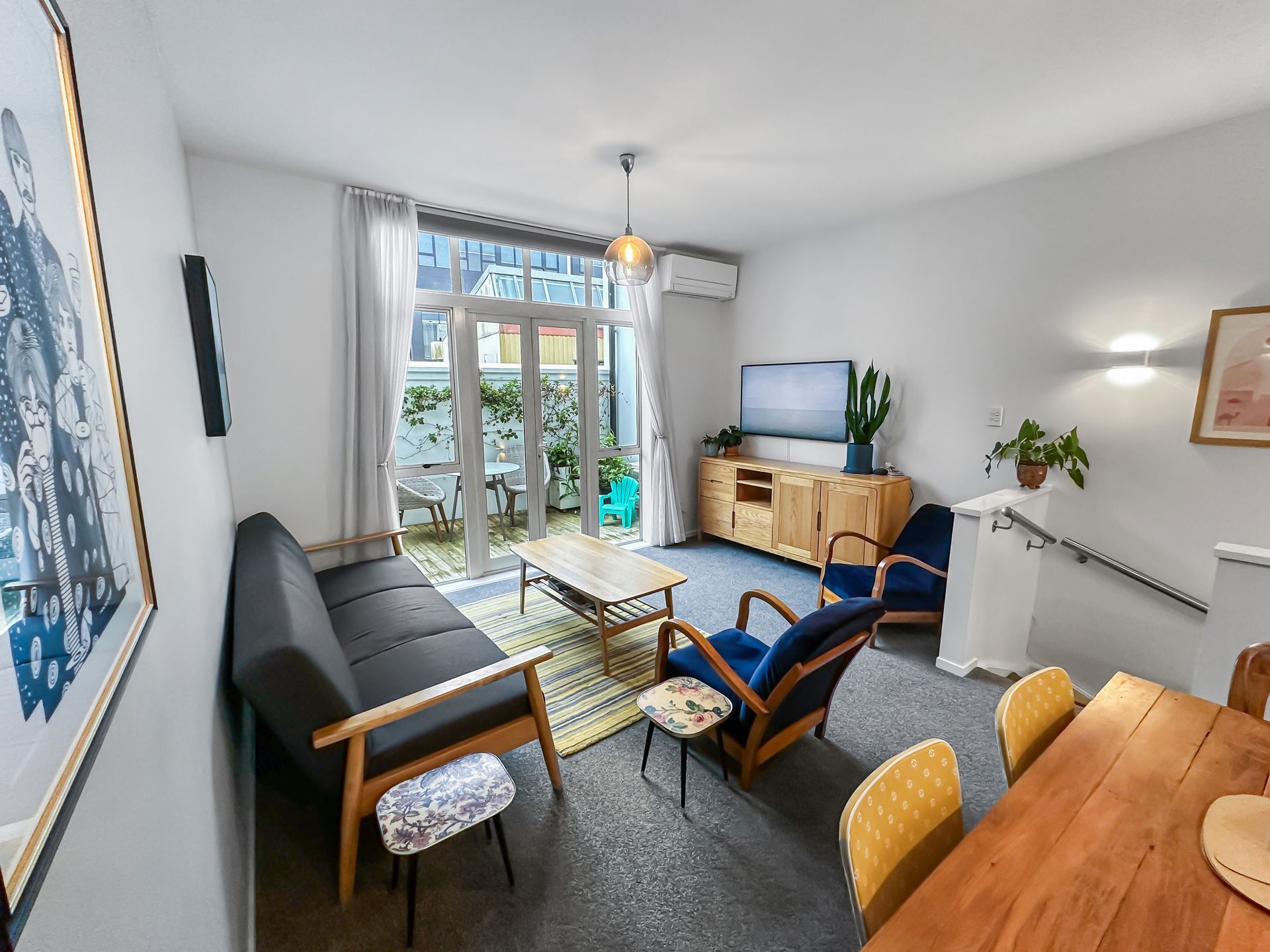 Living room with a black sofa, wooden furniture, and a doorway to a balcony.