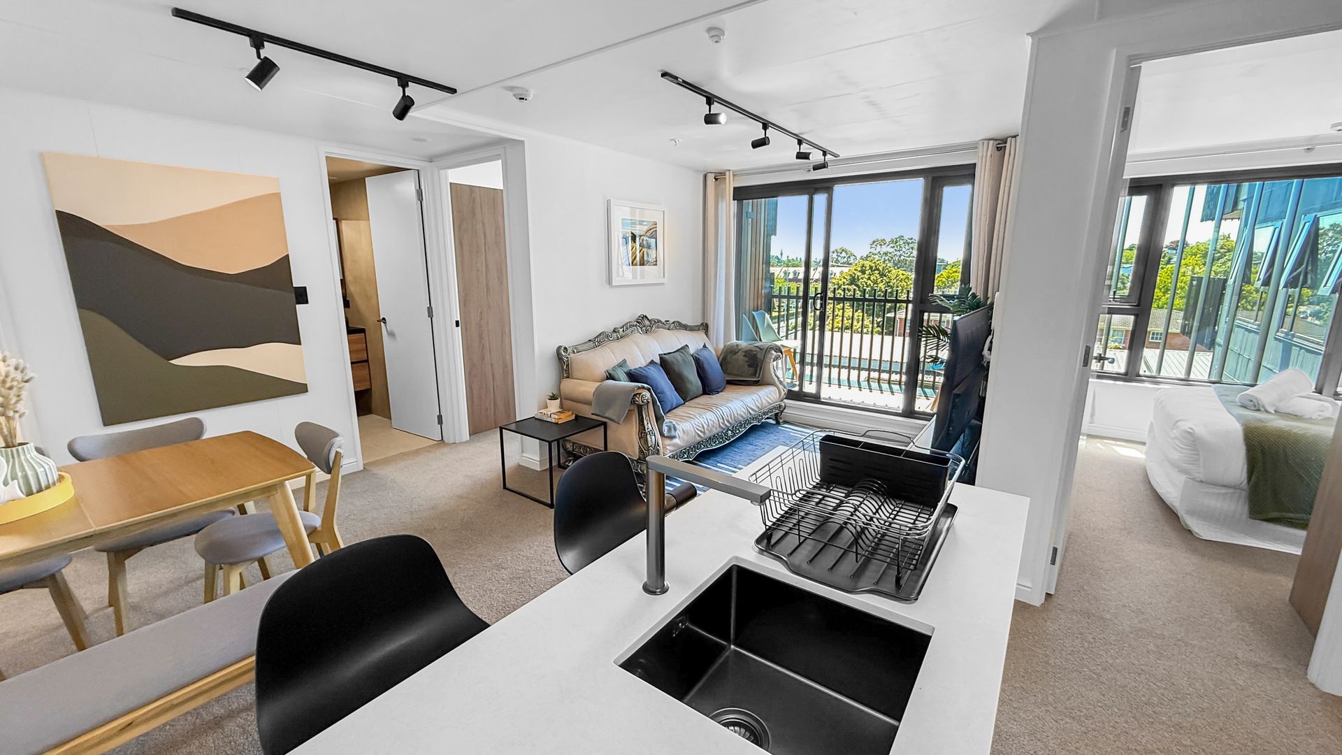 Modern apartment interior with open kitchen, dining, and living areas; bright with balcony view.