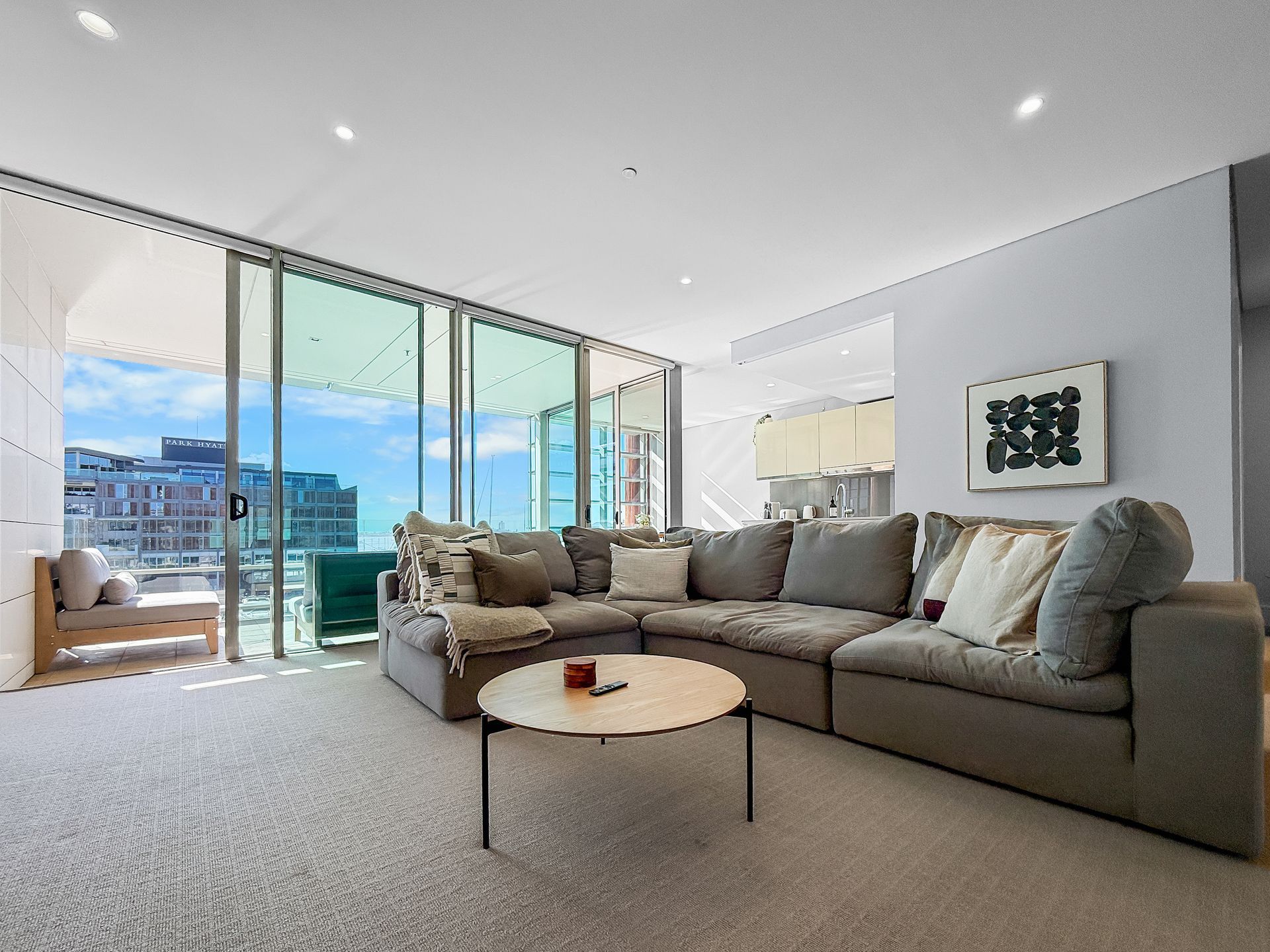 Modern living room with a gray sectional, round coffee table, and balcony with city views.