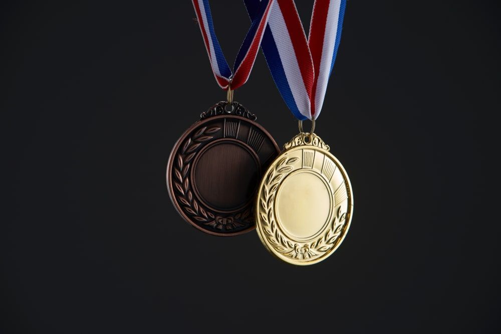 Two Medals One Gold And One Bronze Hanging From Ribbons On A Black Background — Accolades Awards Hunter Valley In Maitland, NSW