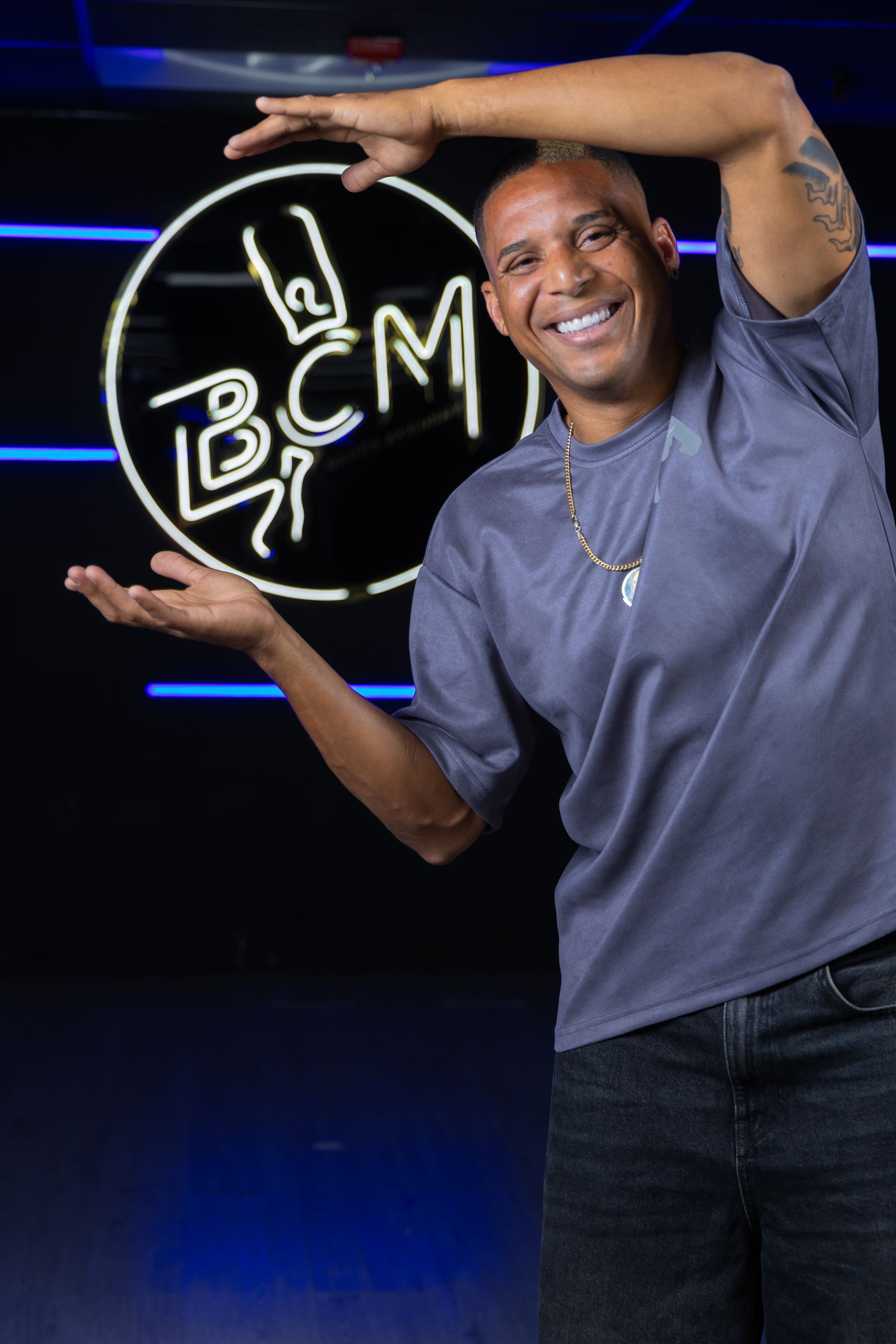 A man is standing in front of a neon sign that says bcm.