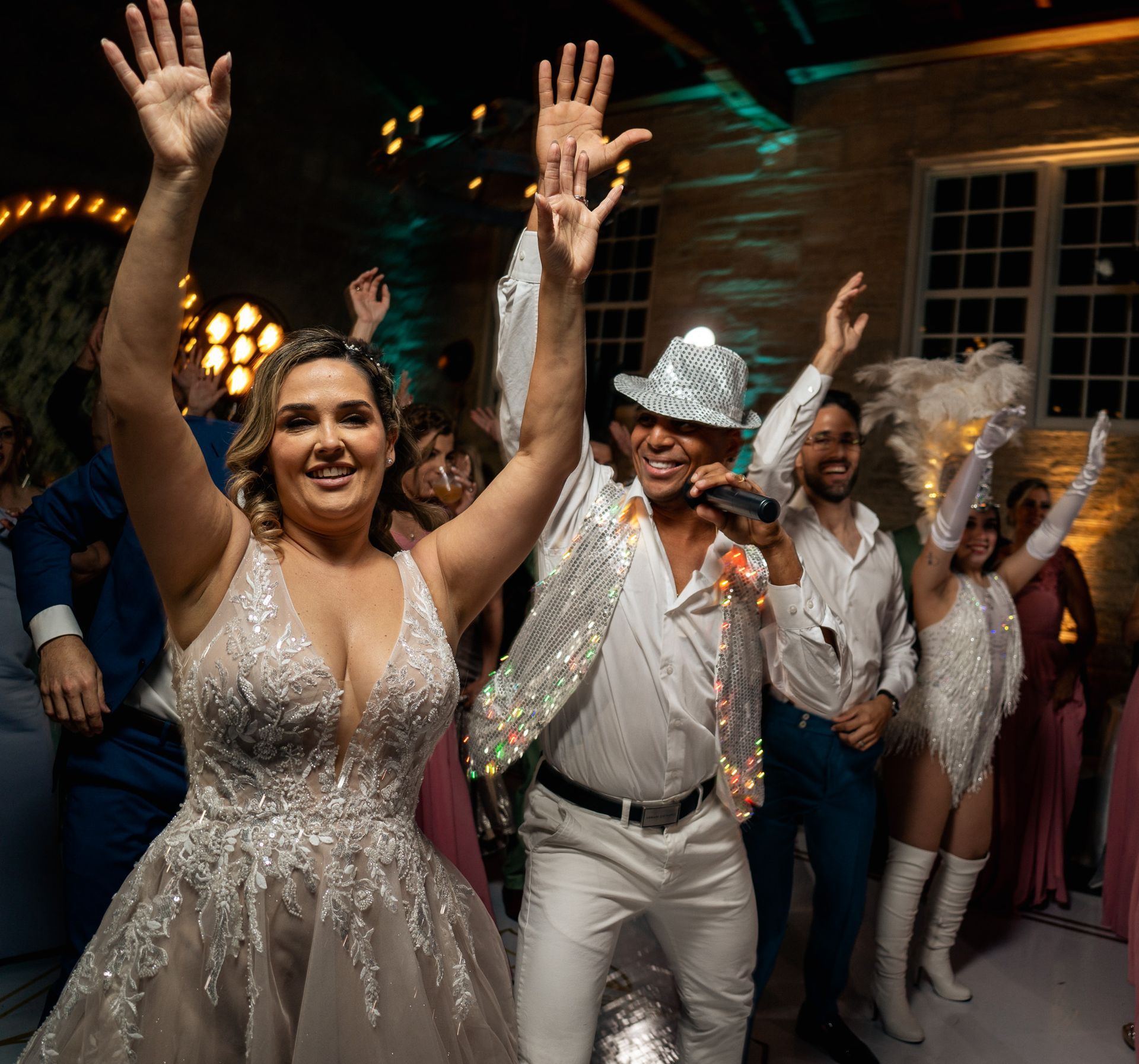 A bride and groom are dancing at a wedding reception while a man sings into a microphone.