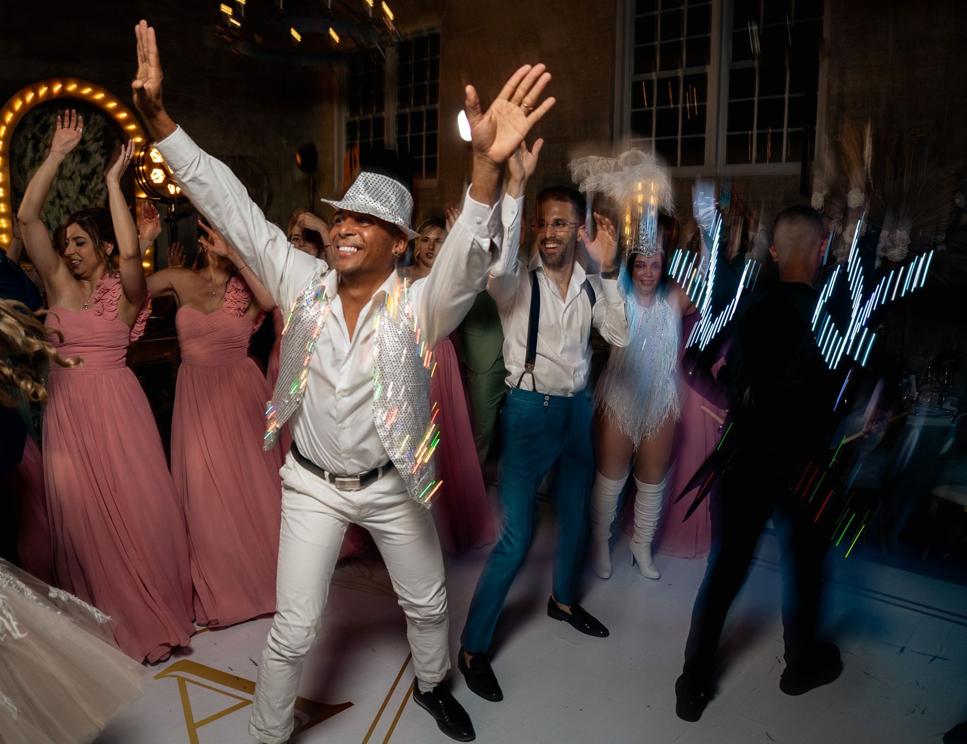 A group of people are dancing on a dance floor at a wedding reception.