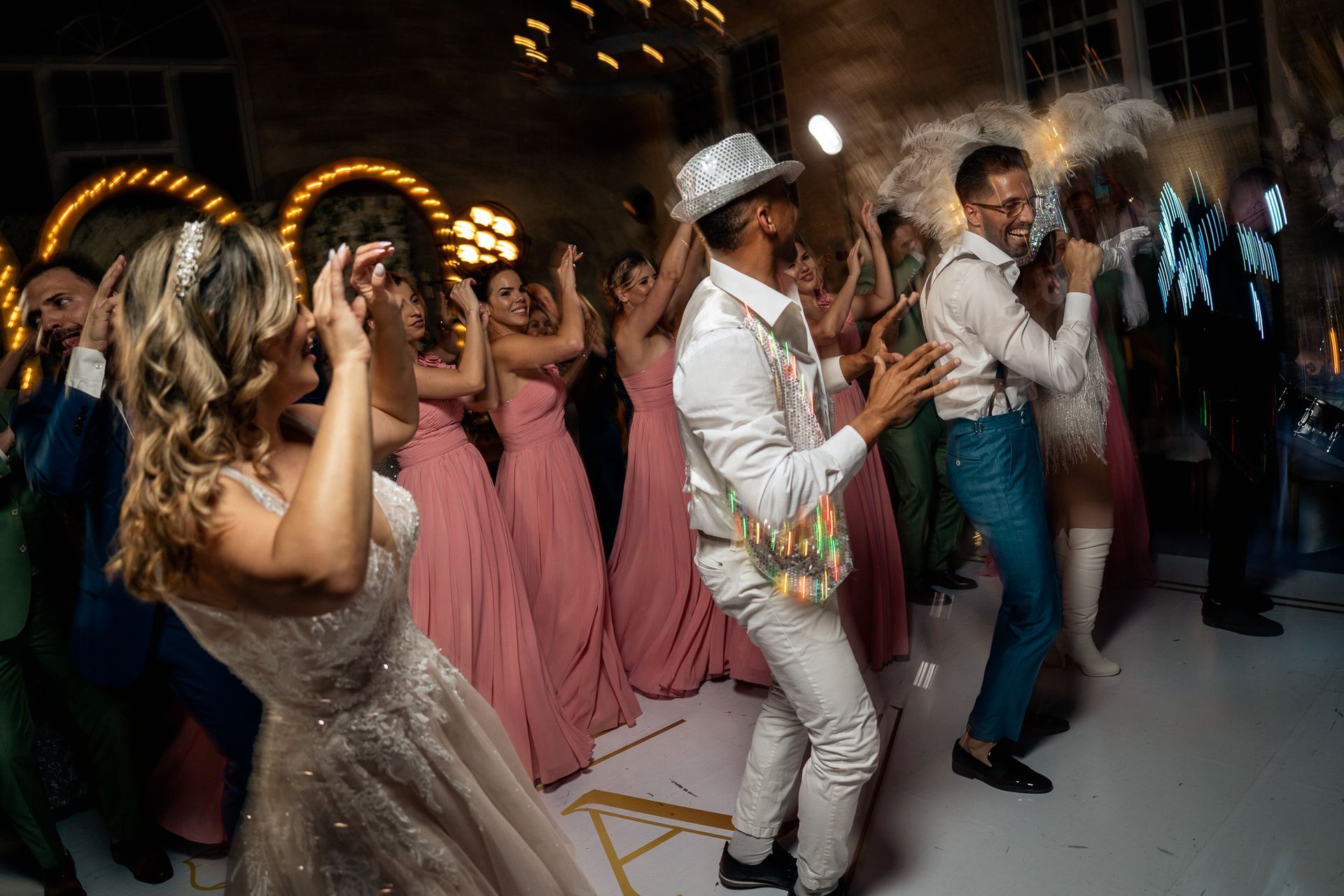 A group of people are dancing at a wedding reception.