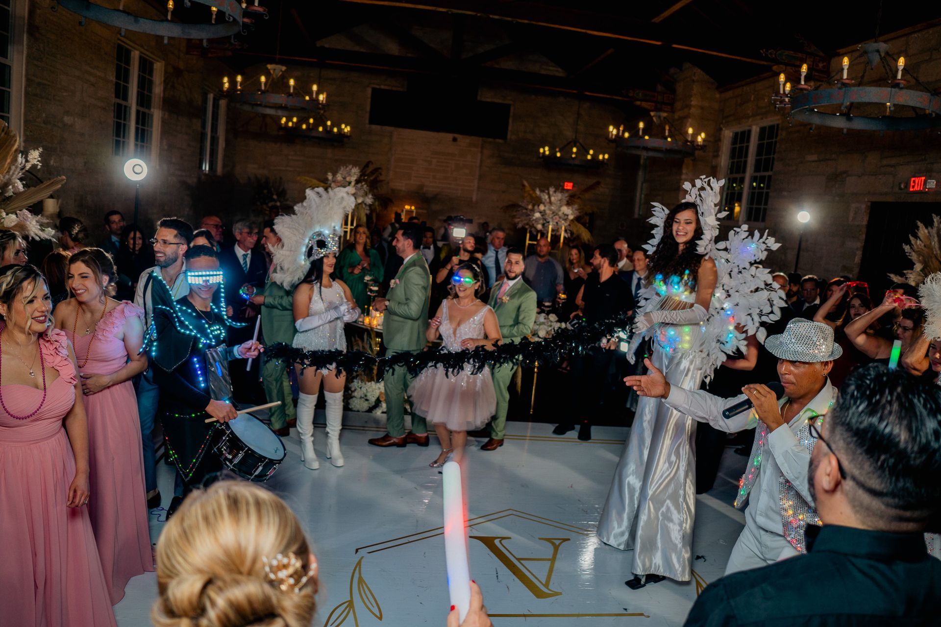 A group of people are dancing in a room at a wedding reception.