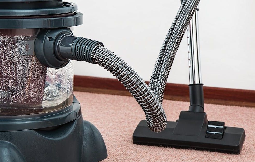 A vacuum cleaner is sitting on a carpet in a room.