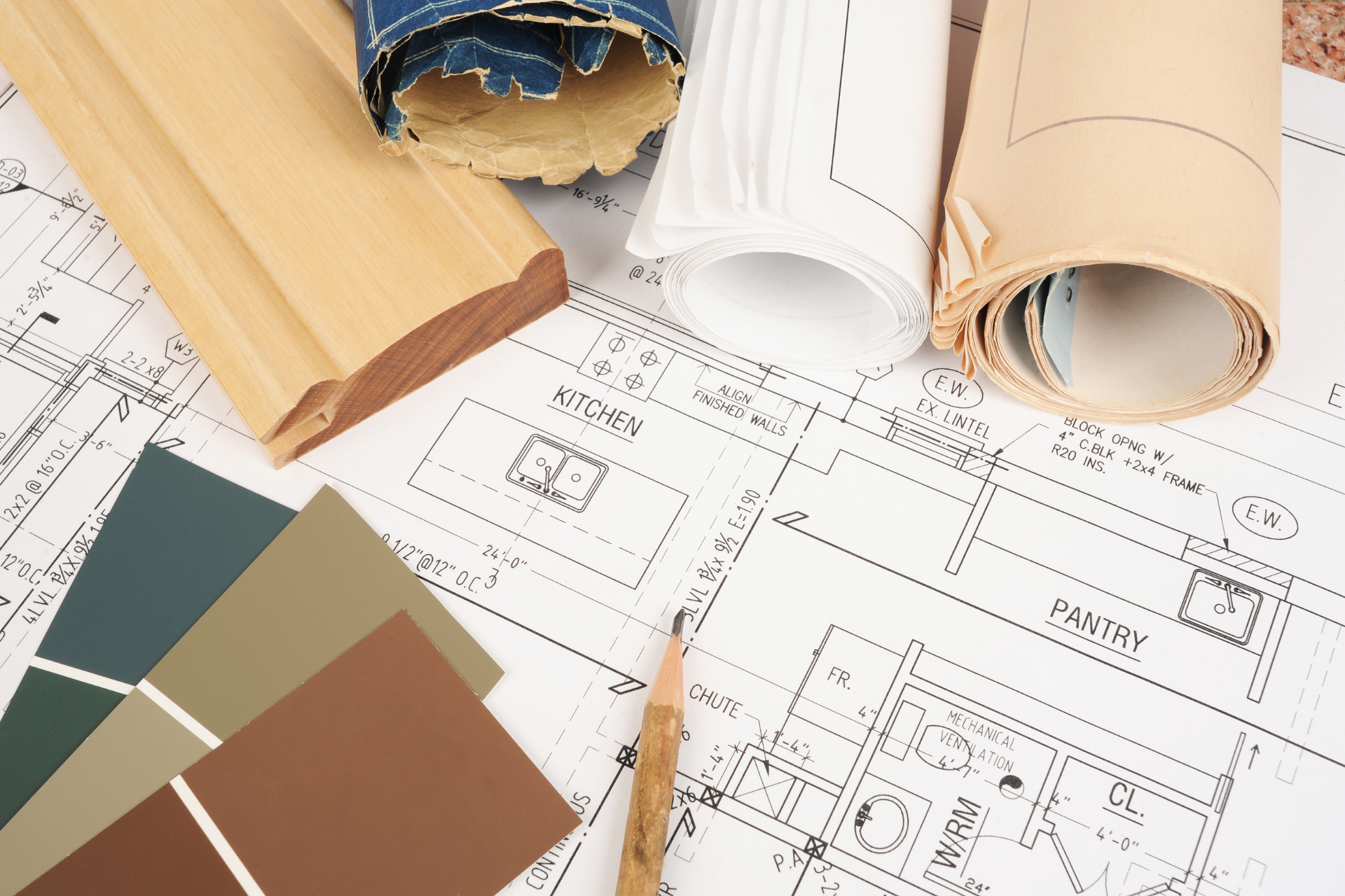 Architectural floor plans with paint swatches and rolled material samples on a desk