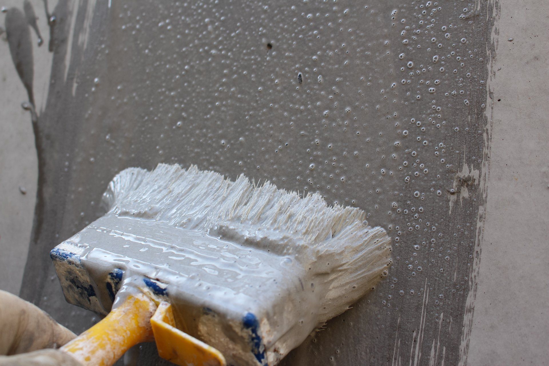 Appliquer de la peinture grise au pinceau sur un mur gris.