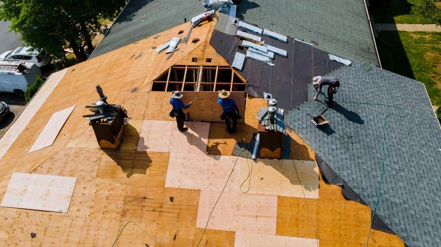 A group of men are working on the roof of a house.