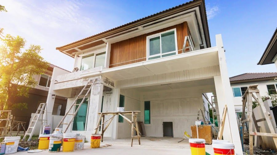A house is being painted with buckets of paint in front of it.