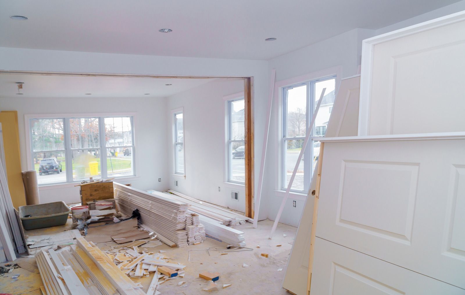 A living room in a house under construction with white doors and windows.