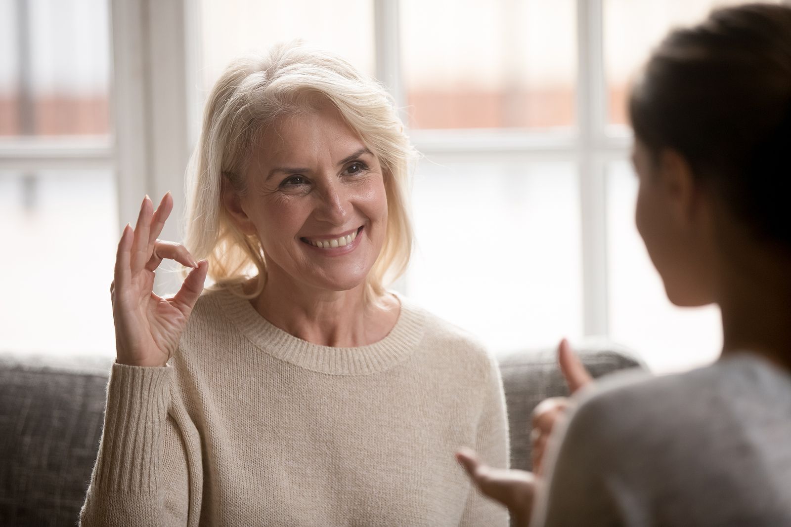 A woman is giving a thumbs up sign while talking to another woman.