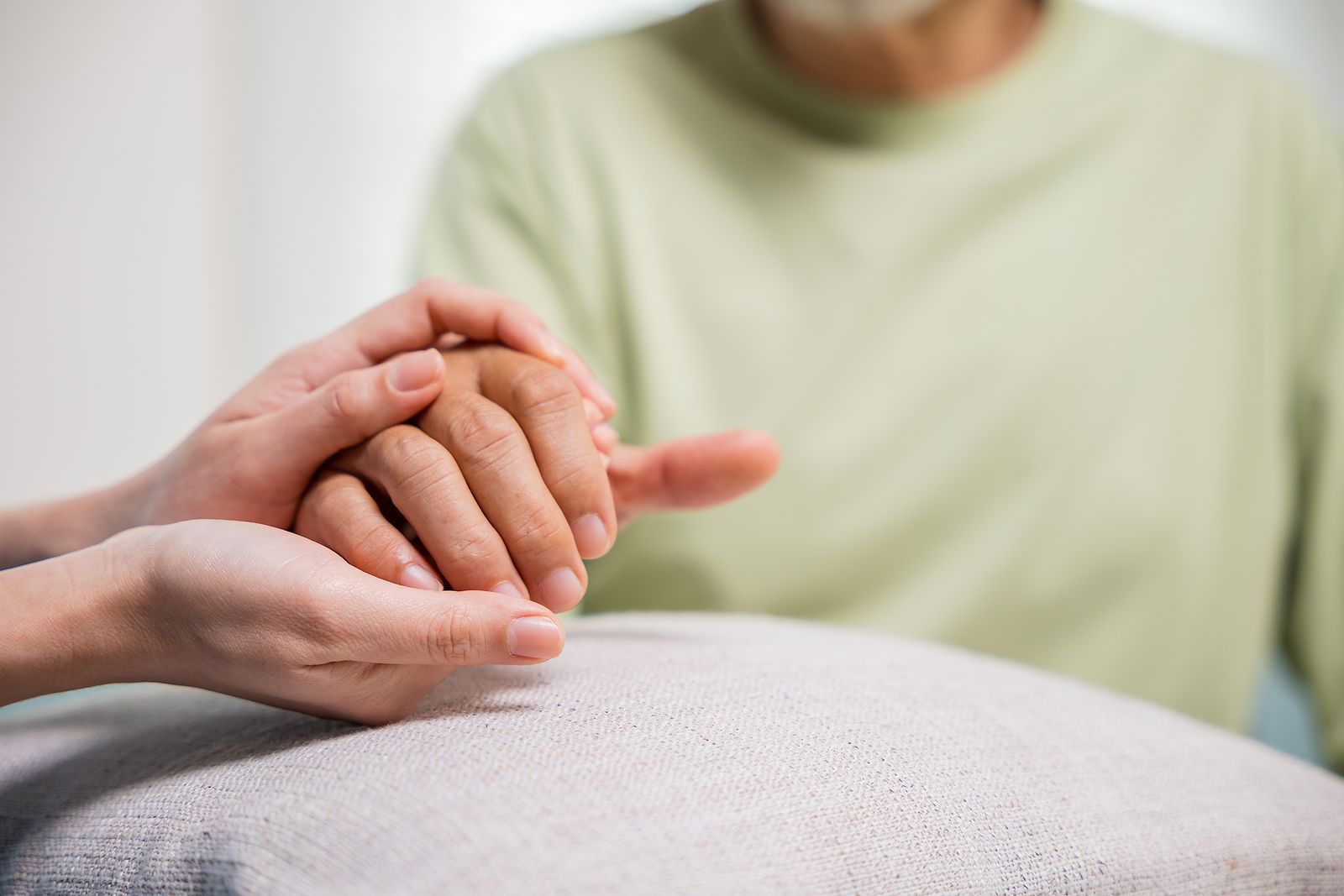 A woman is holding the hand of an elderly man.