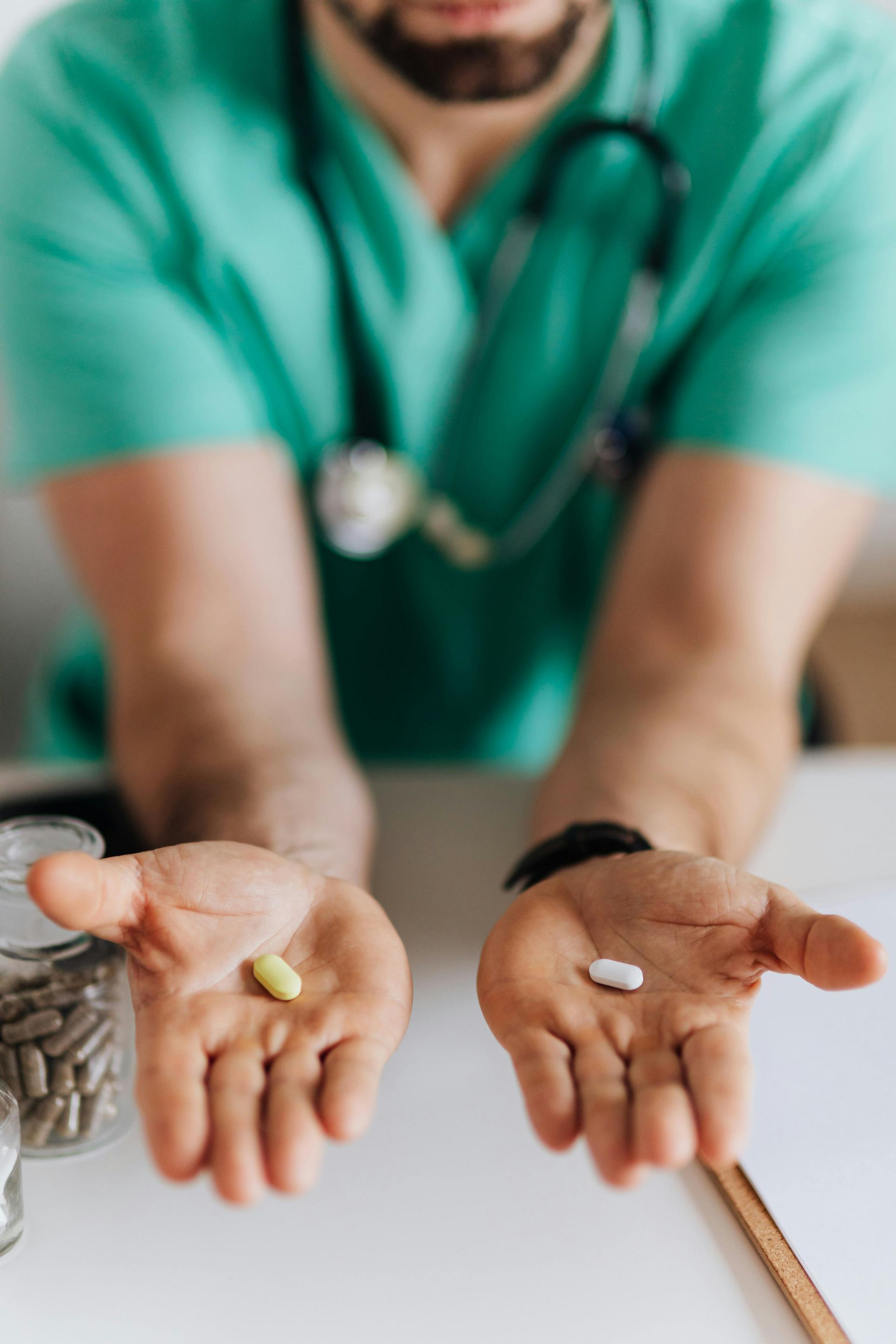 A doctor is holding two pills in his hands.