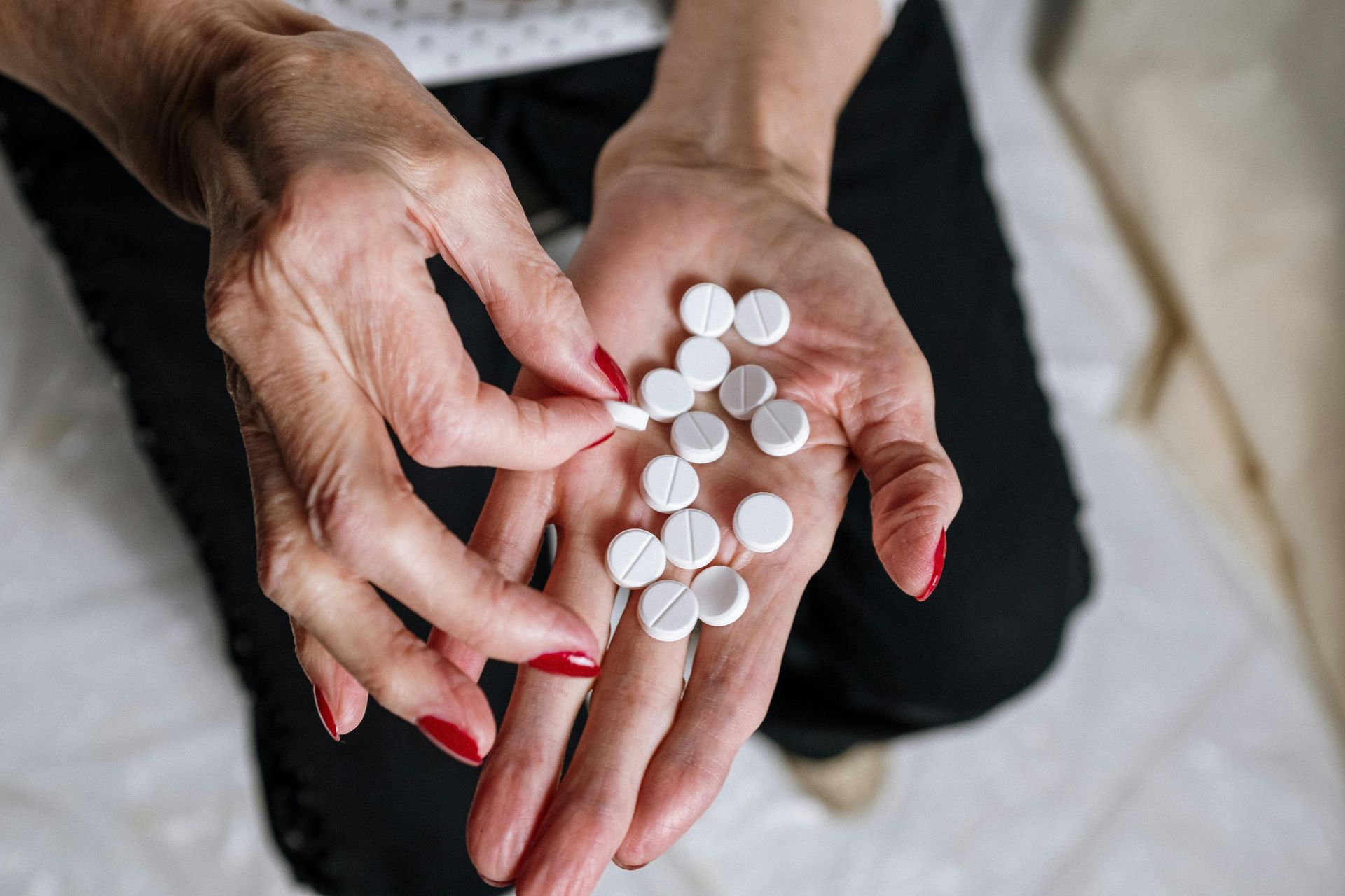 A woman is holding a handful of pills in her hands.