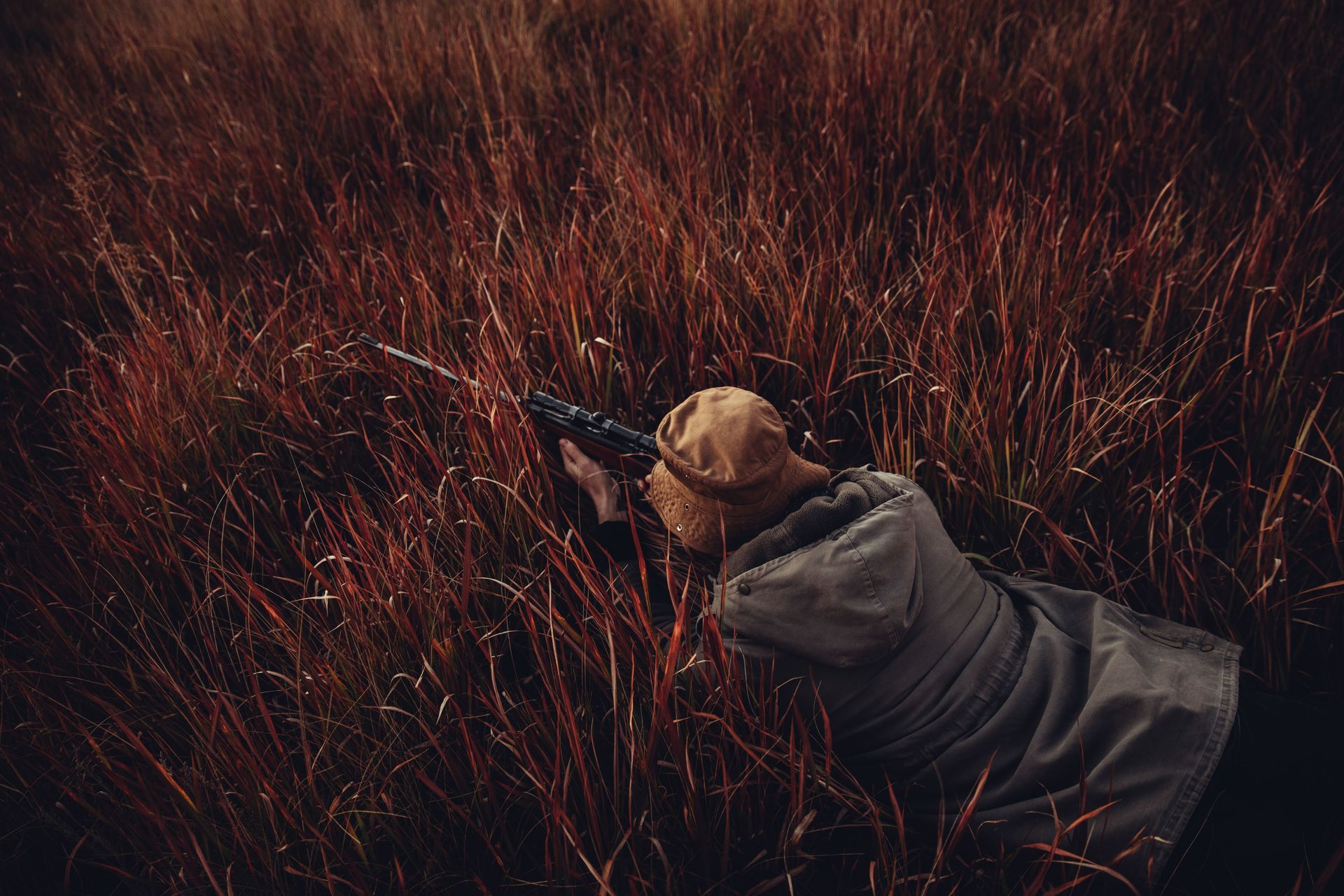hunter aiming prey while laying down