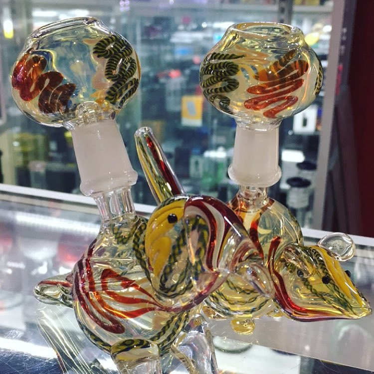 Colorful glass smoking pipes with swirled red, yellow, and green designs on a shop counter