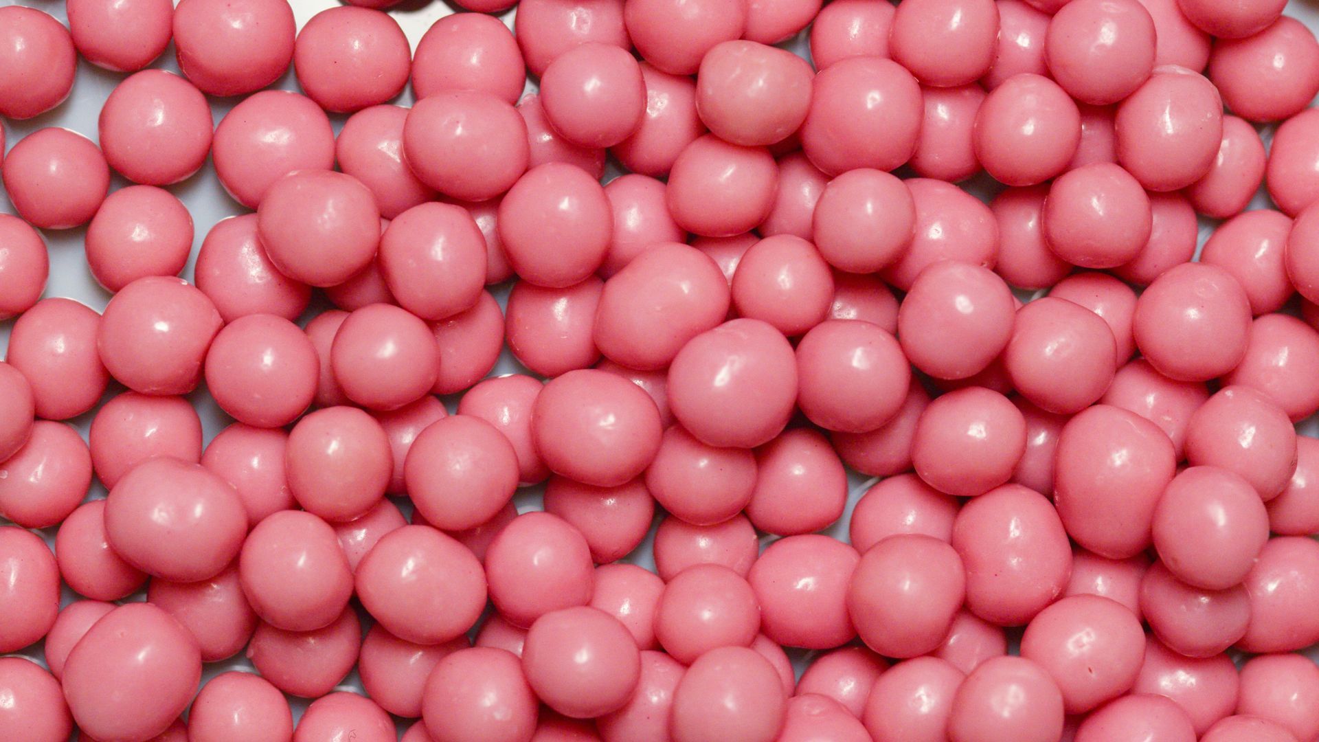 Pile of glossy pink candies filling the frame