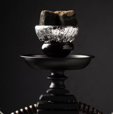 Black sculptural object with a reflective silver band and ribbed base on a dark background