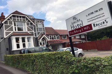 A hotel with cars parked in front of it and a sign in front of it.